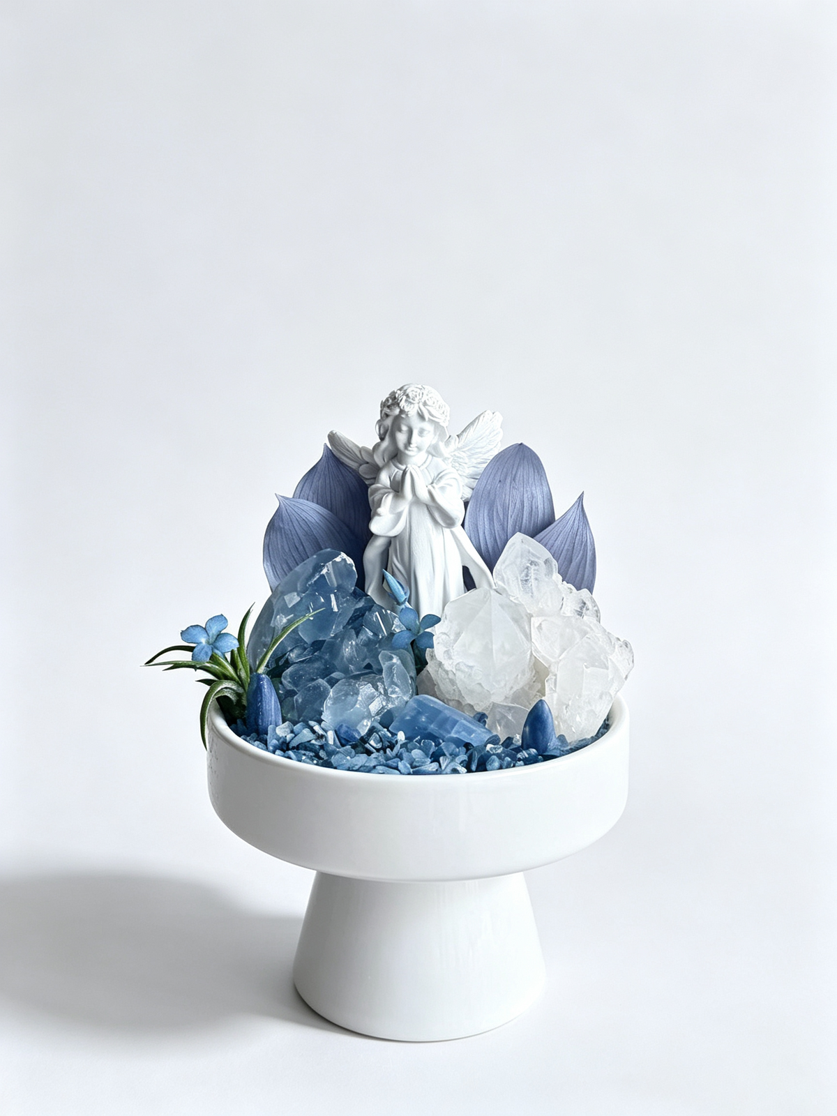 one-of-one crystal garden with porcelain angel, blue celestite, clear quartz, blue kyanite, air plant; front view on pure white background.
