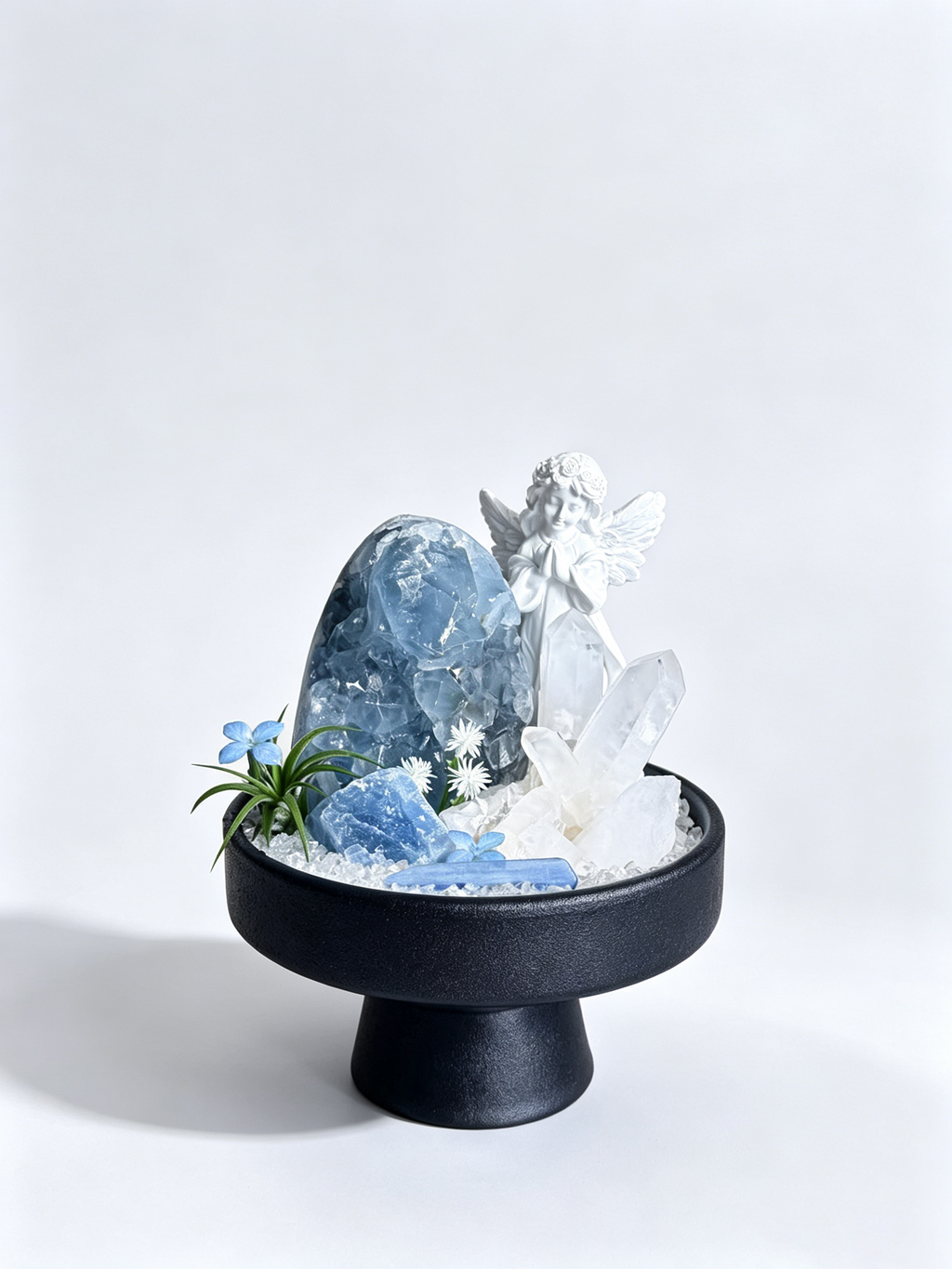 one-of-one crystal garden with porcelain angel, celestite geode egg, clear quartz columns, blue kyanite, air plant; front view on pure white background.
