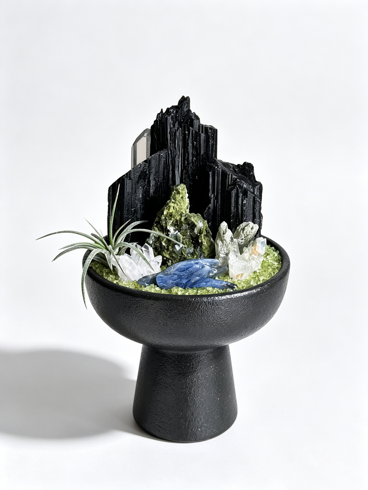 one-of-one crystal garden with black tourmaline, green phantom quartz, blue kyanite, silver air plant; front view on pure white background.
